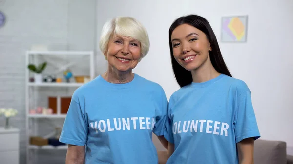 Gönüllü Tişörtlü Olgun Genç Kadınlar Kamerada Gülümsüyor Yardım — Stok fotoğraf
