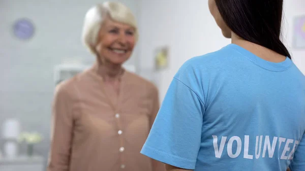 欢快的老太太微笑着向女志愿者 支持在养老院 — 图库照片