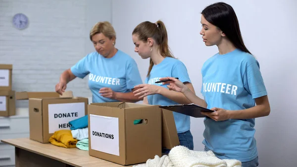 Voluntários Colocando Roupas Caixas Doação Assistente Social Fazendo Anotações Caridade — Fotografia de Stock