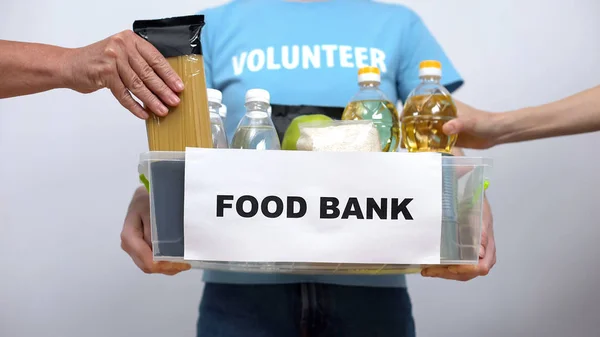志愿者拿着食品银行集装箱 手把提货放在箱子里 — 图库照片