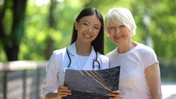 Hemşire Yaşlı Kadın Eklem Röntgen Muayene Sonucu Gösteren Kameraya Gülümseyerek — Stok fotoğraf