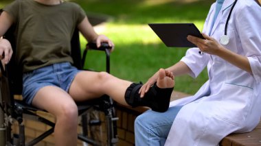 Destekleyici parantez içinde hasta ayak bileği inceleyen tablet ile podiatrist, tıp