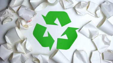 Geri dönüşüm tabelasının etrafında yatan buruşuk tek kullanımlık kağıt bardaklar, doğa konseptini tasarruf edin