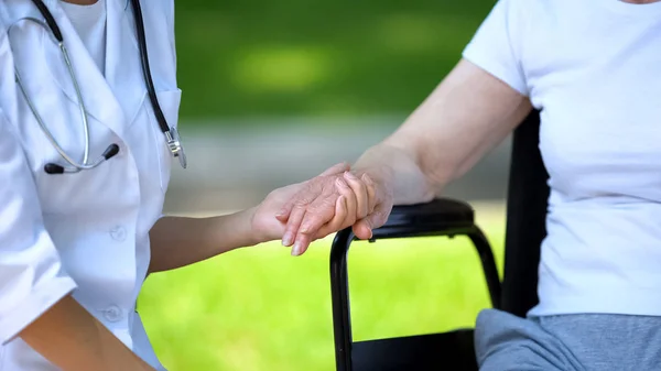 Vrouwelijke Therapeut Holding Hand Van Gehandicapte Oudere Vrouw Rolstoel Buitenshuis — Stockfoto