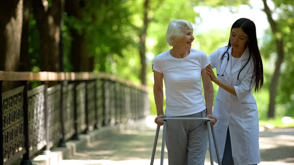 Заботливая Медсестра Помогает Пожилой Женщине Инвалиду Прогулкой Парке Реабилитацией — стоковое фото