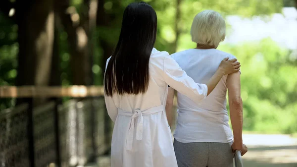 Terapeutka Pomáhající Ženě Chodící Rámy Parku Obnova — Stock fotografie