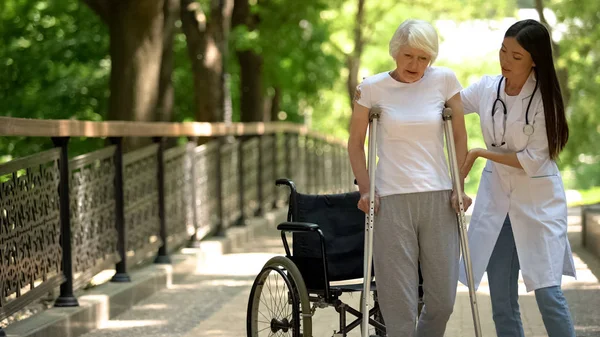 Médico Ajudando Mulher Idosa Deficiente Andando Com Muletas Recuperação Após — Fotografia de Stock