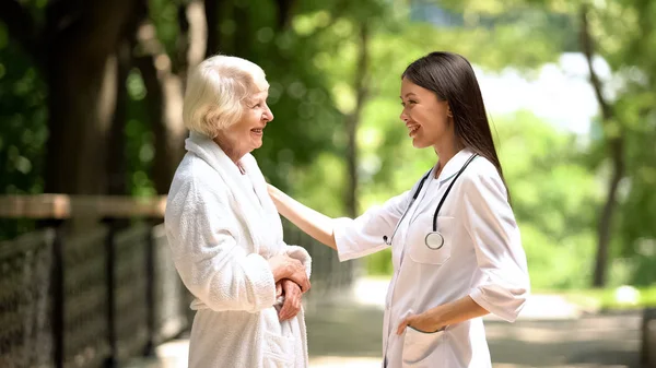 Χαμογελαστή Νοσοκόμα Μιλάει Ηλικιωμένη Γυναίκα Μπουρνούζι Στο Πάρκο Σανατορίων Χαλαρώστε — Φωτογραφία Αρχείου