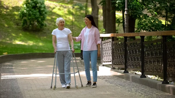 Granddaughter Supporting Disabled Grandma Walking Frame Day Park — Stock Photo, Image