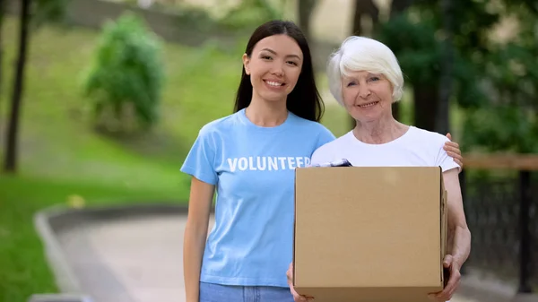 Caring Attivista Femminile Abbracciando Scatola Carte Donazione Della Donna Anziana — Foto Stock