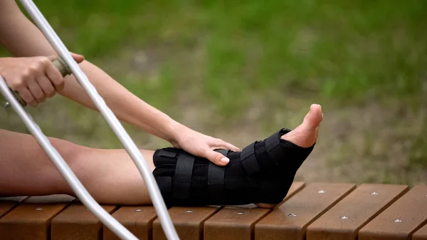 Vrouw Met Enkel Brace Holding Kruk Zittend Buitenshuis Trauma Bandage — Stockfoto