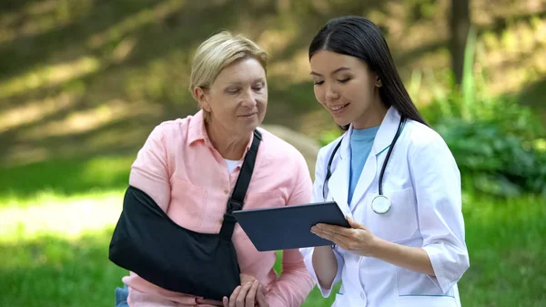 Krankenhausarzt Zeigt Seniorin Mit Armschlinge Tablet App — Stockfoto