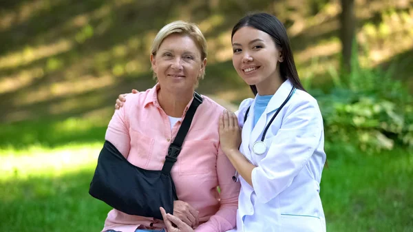 Glücklich Ärztin Umarmt Ältere Dame Schulter Immobilisierung Schlinge Gesundheit — Stockfoto