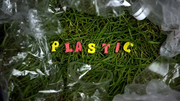 Plastikowe Słowo Otoczone Pustymi Butelkami Trawie Zanieczyszczenie Ekologiczne Recykling — Zdjęcie stockowe