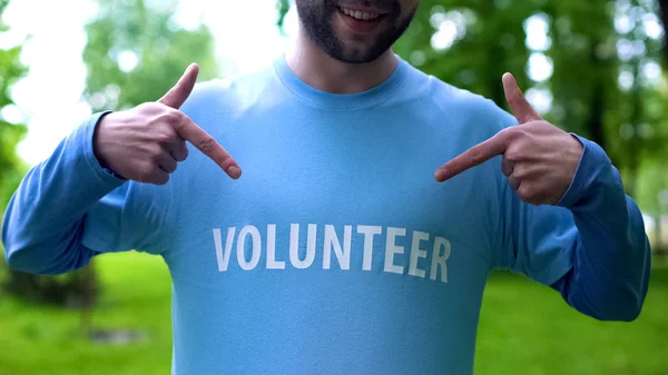微笑的人指着T恤上的志愿者字 野生动物保护 — 图库照片