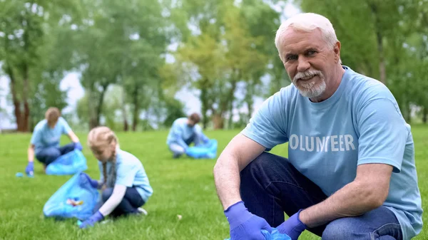 Yaşlı Gönüllü Plastik Çöp Toplama Kamera Eko Olay Bakarak — Stok fotoğraf