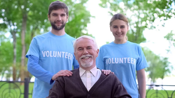 Mutlu Yaşlı Adam Kamera Gülümseyen Iki Gönüllü Yaşlı Insanlar Destek — Stok fotoğraf