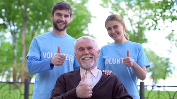 Jubelnde Rentnerin Und Zwei Ehrenamtliche Zeigen Daumen Hoch Sozialhilfefonds — Stockfoto