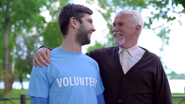 年轻的男性志愿者和成熟的绅士互相微笑 社会支持 — 图库照片