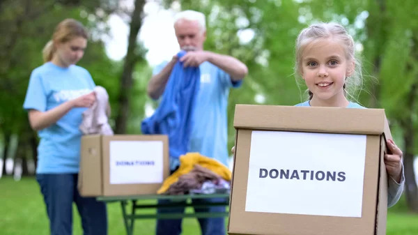 Uśmiechnięta Dziewczyna Trzymanie Pudełko Darowizny Wolontariuszy Przygotowujących Pomoc Humanitarną Pomoc — Zdjęcie stockowe