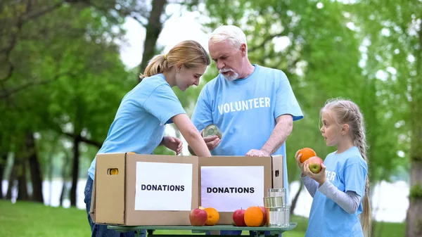 缶詰や果物の寄付箱を置くボランティア 貧しい人々の援助 — ストック写真
