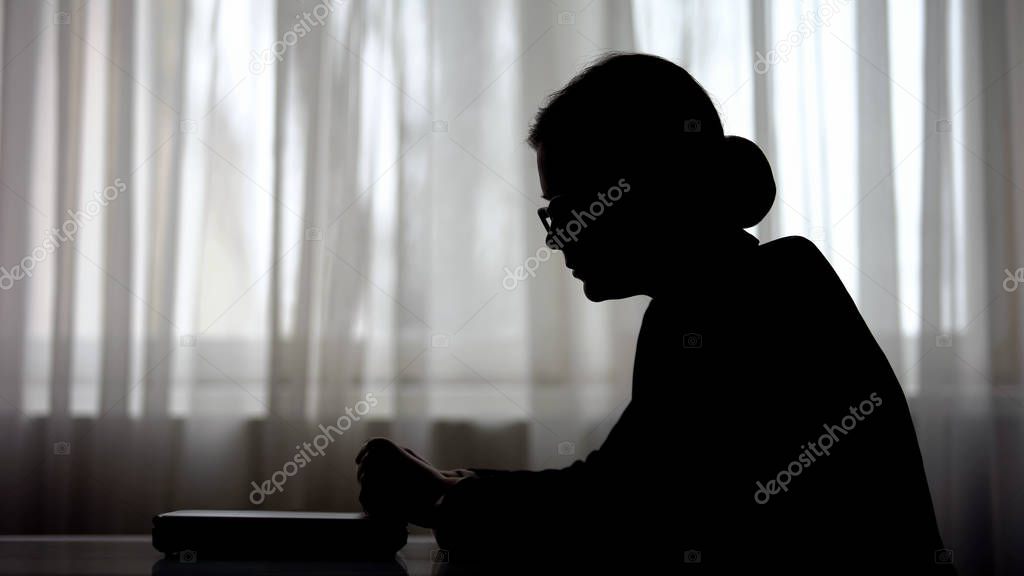 Silhouette of tired business woman with closed laptop after working overtime