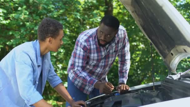 Amerykański ojciec wyjaśniając strukturę samochodu do syna pokazując części samochodowe, razem — Wideo stockowe