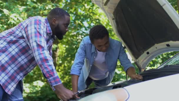 Papá golpeando cabeza arriba regañando hijo reparar coche juntos, crianza de los niños — Vídeos de Stock