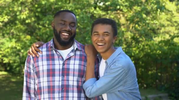 Alegres hermanos americanos sonriendo en la cámara al aire libre, conexión familiar, diversión — Vídeos de Stock