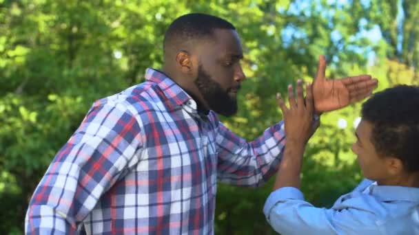 Irritado homem negro tentando bater adolescente criança do sexo masculino, conflito familiar, puberdade idade — Vídeo de Stock