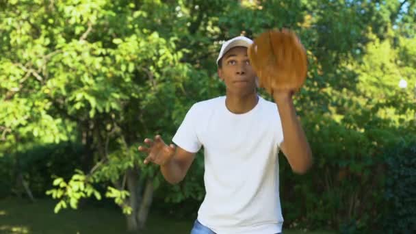 Ευτυχισμένος μαύρος έφηβος φορώντας λευκό καπέλο λαμβάνοντας και ρίχνοντας μπέιζμπολ — Αρχείο Βίντεο