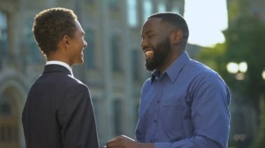 Heyecanlı Afrikalı bir adam mezuniyet elbisesi içindeki oğluyla gurur duyuyor.