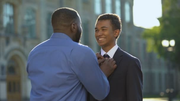 Blij ouder knuffelen jonge zoon in pak buiten universiteit, bal viering — Stockvideo
