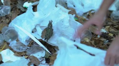 Eller plastik torba içinde çöp topluyor. Toprağı temizliyor, doğa ekolojisi ile ilgileniyor.