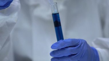 Araştırmacı tüpten biyolojik tehlike sıvısı alıyor, silah geliştirme, tehlike