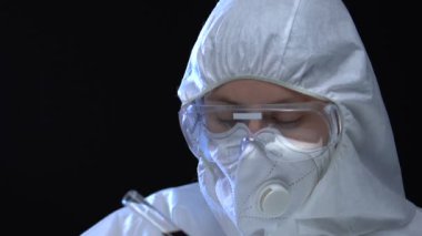 Beyaz üniformalı kimyager test tüplerinde ve virüslerde tehlikeli sıvılar gösteriyor.