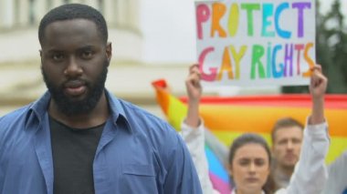 Siyah adam, Lgbt hakları için protestocularla birlikte gökkuşağı kalbini yükseltiyor.