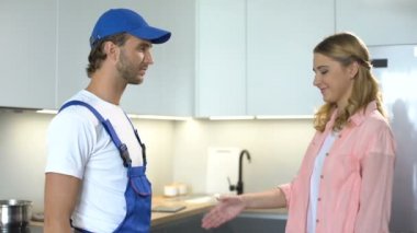 Becerikli adam tatmin olmuş kadın müşteriyle el sıkışıyor, profesyonel tamir hizmetleri.
