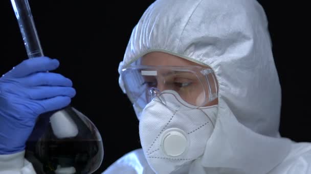 Γυναίκα χημικός με στολή που κρατά επικίνδυνη ουσία σε φιάλη, παράνομο εργαστήριο — Αρχείο Βίντεο