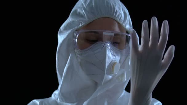 Koruyucu gözlüklü ve solunum cihazlı kadın araştırmacı eldiven takıyor. — Stok video