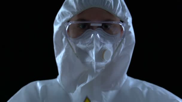Výzkumník v ochranném obleku ukazující radiační znamení kameře, neviditelné nebezpečí — Stock video