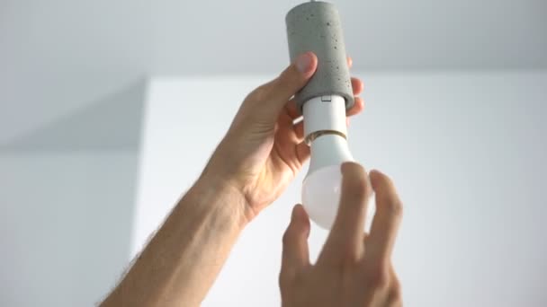 Male hands twisting electrical saving lightbulb, energy efficiency, closeup — ストック動画