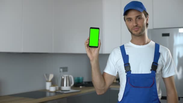 Man in uniform met telefoon met groen scherm, boeking van huis reparatieservice — Stockvideo