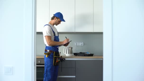 El hombre que escribe factura para el mantenimiento de la casa, marido por una hora, servicio de reparación — Vídeos de Stock