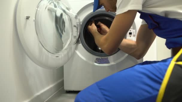 Форман в униформе ремонт стиральной машины с помощью отвертки, техническое обслуживание — стоковое видео