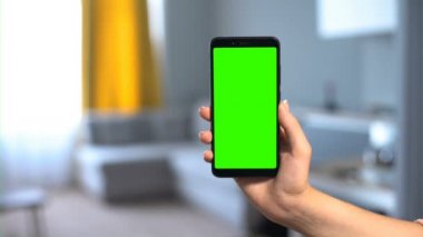 Oda içi arka planda el ele tutuşan telefon, online otel rezervasyonu uygulaması