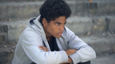 Mutsuz hasta erkek çocuk şehir merdivenlerinde tek başına oturuyor, evden kaçıyor, umutsuzluk içinde.