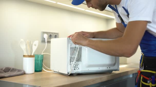 Handwerker mit Schraubenzieher zu reparieren Mikrowelle, Haushaltsgerät Reparatur, Garantie — Stockvideo