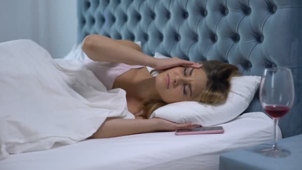 Dronken vrouw wakker met hoofdpijn, kijken naar leeg wijnglas, vrouwelijk alcoholisme — Stockvideo
