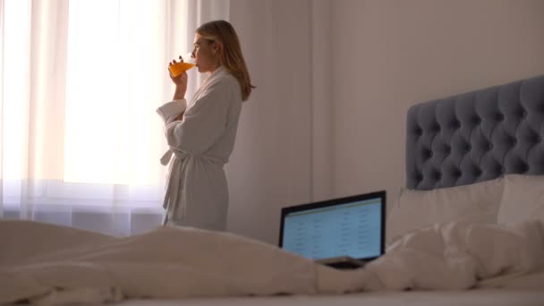 Computadora portátil con lista de vuelos u hoteles, mujer bebiendo jugo, reserva de viajes — Vídeo de stock